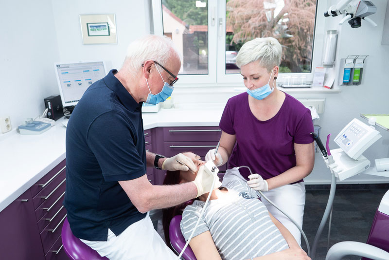 Herr Dr. Kensche und Mitarbeiterin bei der Zahnbehandlung einer Patientin